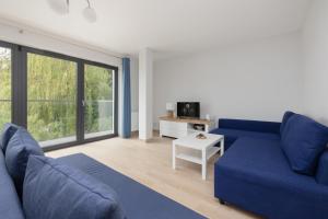 ein Wohnzimmer mit einem blauen Sofa und einem großen Fenster in der Unterkunft Jantar Apartamenty Siedem Wysp in Sianożęty