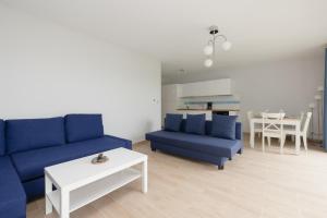 ein Wohnzimmer mit einem blauen Sofa und einem Tisch in der Unterkunft Jantar Apartamenty Siedem Wysp in Sianożęty