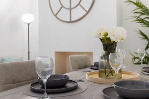 una mesa de comedor con vasos y flores blancas en un jarrón en City Reach by Staytor Accommodation, en Exeter