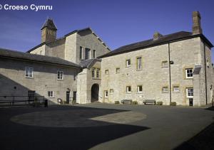 a large stone building with a courtyard in front of it at The Stables in Corwen