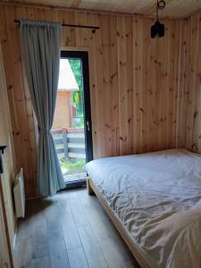 a bedroom with a bed and a large window at Zalesie 7D - domek z 2 sypialniami przy plaży. in Zalesie