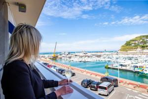 a woman standing on a balcony looking out at a marina at Hotel Le Grand Pavois in Fécamp