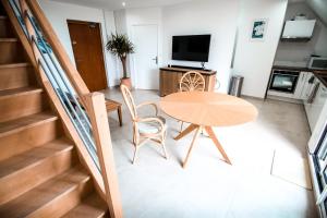 Cette chambre dispose d'une table, de chaises et d'une télévision. dans l'établissement APPART-DUPLEX VUE MER PANORAMIQUE BALCON & PISCINE proche commerce, à Penmarcʼh