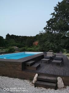 una piscina con 2 sillas y una terraza de madera en Antico Palmento dell'Etna, en Pedara