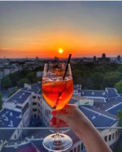 a person holding a drink with the sunset in the background at Metropol Palace, Belgrade in Belgrade
