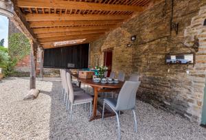 a wooden table and chairs sitting under a brick wall at Lower Fifehead Farm in Sturminster Newton