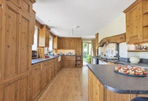 een grote keuken met houten kasten en een fruitschaal op het aanrecht bij Creaky Cottage in Dorchester