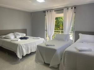 2 camas en una habitación con ventana en Pousada Maria`s Inn - Conforto, acolhimento e qualidade em Foz do Iguaçu en Foz do Iguaçu