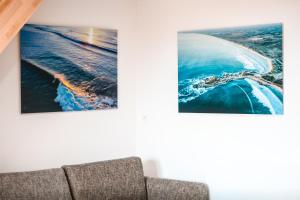 um sofá numa sala de estar com duas fotografias na parede em APPART-DUPLEX VUE MER PANORAMIQUE BALCON & PISCINE proche commerce em Penmarcʼh