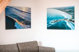 a couch in a living room with two pictures on the wall at APPART-DUPLEX VUE MER PANORAMIQUE BALCON & PISCINE proche commerce in Penmarch
