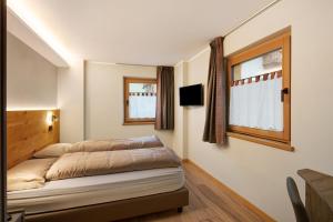 een slaapkamer met een bed en twee ramen bij Sun Mountain Planet Suite House in Livigno
