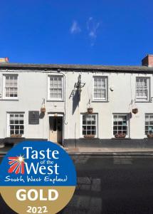 un edificio blanco con una señal que lee el sabor del oro del oeste en The Thirsty Scholar, en Penryn