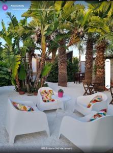 un patio con sillas, una mesa y palmeras en B&B Estremo Sud Marzamemi, en Marzamemi