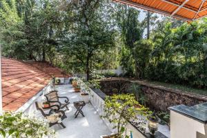 an outdoor patio with chairs and plants and trees at StayVista at Vintage Hideaway Pet-Friendly Paradise with Private Pool in Porvorim