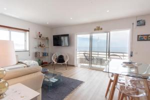 uma sala de estar com um sofá e vista para o oceano em Apartamento Mar e Sol na Nazaré