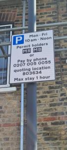 una señal de estacionamiento en un poste frente a un edificio de ladrillo en Stylish home in Streatham., en Londres