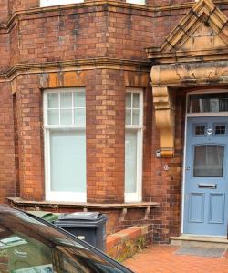 ロンドンにあるStylish home in Streatham.の青いドアと2つの窓があるレンガ造りの建物