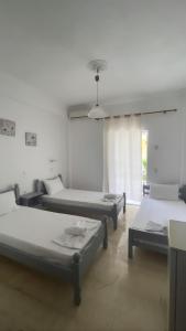 a room with three beds and a window at Lemon Grove Hotels And Studios in Kavos