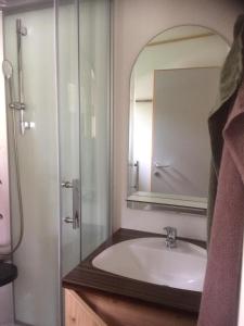 a bathroom with a sink and a shower with a mirror at Polzer CAMPING BÜKFÜRDŐ in Bük