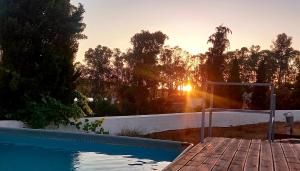 a swimming pool with the sunset in the background at Palacete Dos Alcaides in Minas de São Domingos