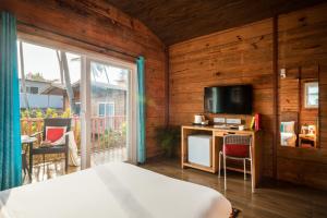 a bedroom with a bed and a television and a balcony at Mariners Bay Beach Resort in Arambol