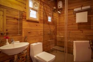 a bathroom with wooden walls and a toilet and a sink at Mariners Bay Beach Resort in Arambol