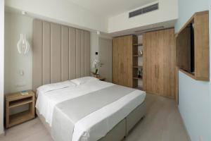 a bedroom with a large white bed and a tv at Hotel Rex in Livorno