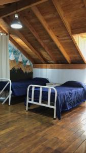 a bedroom with two beds and a wooden ceiling at Berkana hostel Bariloche in San Carlos de Bariloche