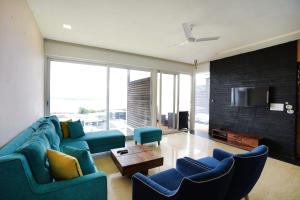 a living room with blue couches and a tv at St Jacinto Island Villa By JadeCaps- Bay View and Infinity Pool Near Goa Airport in Dabolim