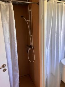 eine Dusche im Bad mit einem weißen Duschvorhang in der Unterkunft Tiny House Marielyst in Bøtø By