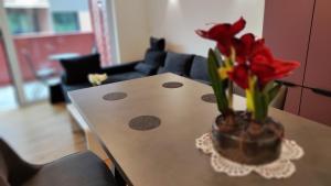 een tafel met een vaas met rode bloemen erop bij Apartment Ozare in Slovenj Gradec