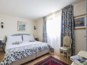 a bedroom with a bed and a chair and a window at Hotel Villa Stella in Venice-Lido