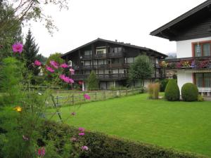 ein großes Haus mit einem Hof mit rosa Blumen in der Unterkunft Haus St. Georg in Maria Alm am Steinernen Meer