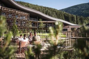 un gruppo di persone seduti ai tavoli fuori da un edificio di Falkensteiner Family Resort Lido Superior a Chienes