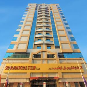 沙迦的住宿－Sharjah Royal Tulip Hotel Apartments توليب رويال الشارقة，一座高大的建筑,上面标有酒店标志