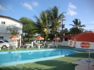 a swimming pool with tables and umbrellas next to a building at Hotel Pousada Terras do Sem Fim in Olivença