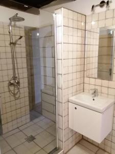 a white tiled bathroom with a shower and a sink at Szentmária Vendégház in Tarnaszentmária
