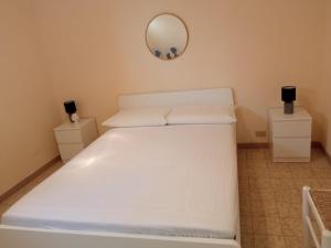 una camera da letto con un letto bianco e uno specchio a parete di Villetta indipendente in villaggio a 2 passi dal mare a Santa Maria al Bagno