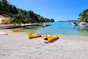 dwa kajaki siedzące na plaży obok wody w obiekcie Villa Green Bay w mieście Vela Luka