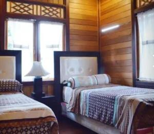 1 dormitorio con 2 camas, lámpara y ventanas en The Kulawi Villa & Resort, en Puncak 20 fotos más
