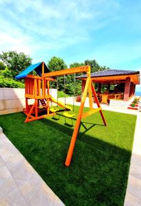 plac zabaw ze strukturą zabaw na trawie w obiekcie Apartmani Vesna w mieście Opric