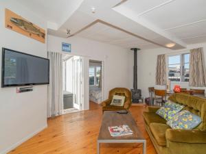 una sala de estar con un sofá y una mesa en Pipi Palace - Whangamata Bach, en Whangamata