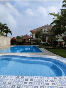 una gran piscina azul con una casa en el fondo en The Kulawi Villa & Resort, en Puncak