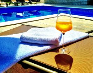 kieliszek wina siedzący na stole obok basenu w obiekcie Apartmani Vesna w mieście Opric