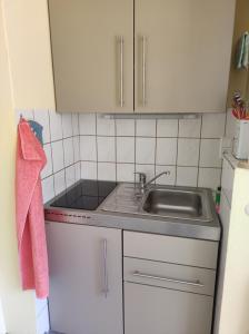 una pequeña cocina con fregadero y armarios blancos en Ferienhaus Hering, en Neu Porschdorf