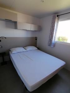 1 cama blanca grande en una habitación con ventana en SAFRED Mobile Home Portbail-sur-Mer en Portbail