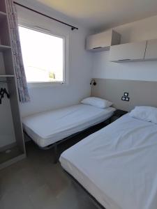2 camas en una habitación pequeña con ventana en SAFRED Mobile Home Portbail-sur-Mer en Portbail