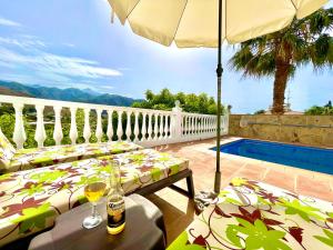 een patio met een tafel, een parasol en een zwembad bij Villa Nuria in Frigiliana