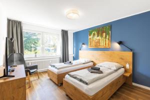 a hotel room with two beds and a desk at Glück Auf Appartements Am Stadtpark Duisburg in Duisburg