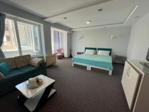 a bedroom with a bed and a couch and a table at White Rose Guest Rooms in Burgas